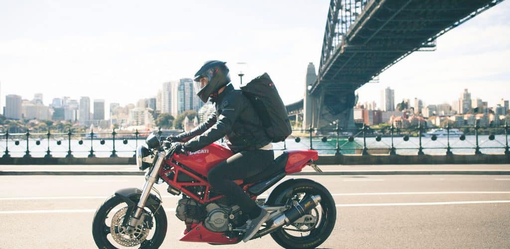 Man on a red motorcycle wearing Henty Commuter Bag: the Wingman backpack